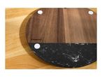 Round wooden and marble serving board on a wooden table.