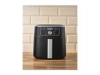 A black digital air fryer on a wooden countertop against a tiled wall.