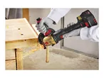 Cordless angle grinder cutting a metal pipe, creating sparks on a wooden workbench.