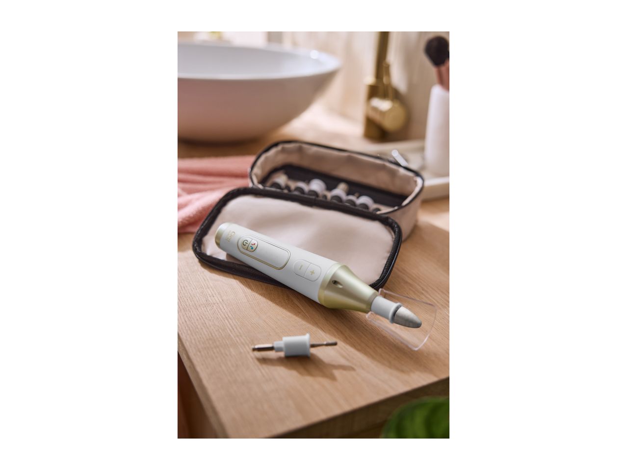Electric manicure and pedicure set with various attachments in a case on a wooden surface.