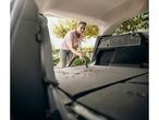 Una donna pulisce il bagagliaio della sua auto con un aspirapolvere.