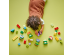 Child playing with colorful building blocks, including flower and butterfly shapes, on a green surface.