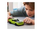 A boy playing with a lime green toy car on a grey surface.