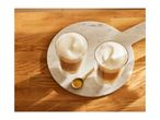 Two glasses of latte macchiato with frothy milk on a marble board and wooden table