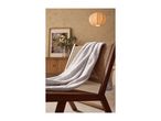 A light gray textured blanket draped over a wooden and wicker chair in a living room.