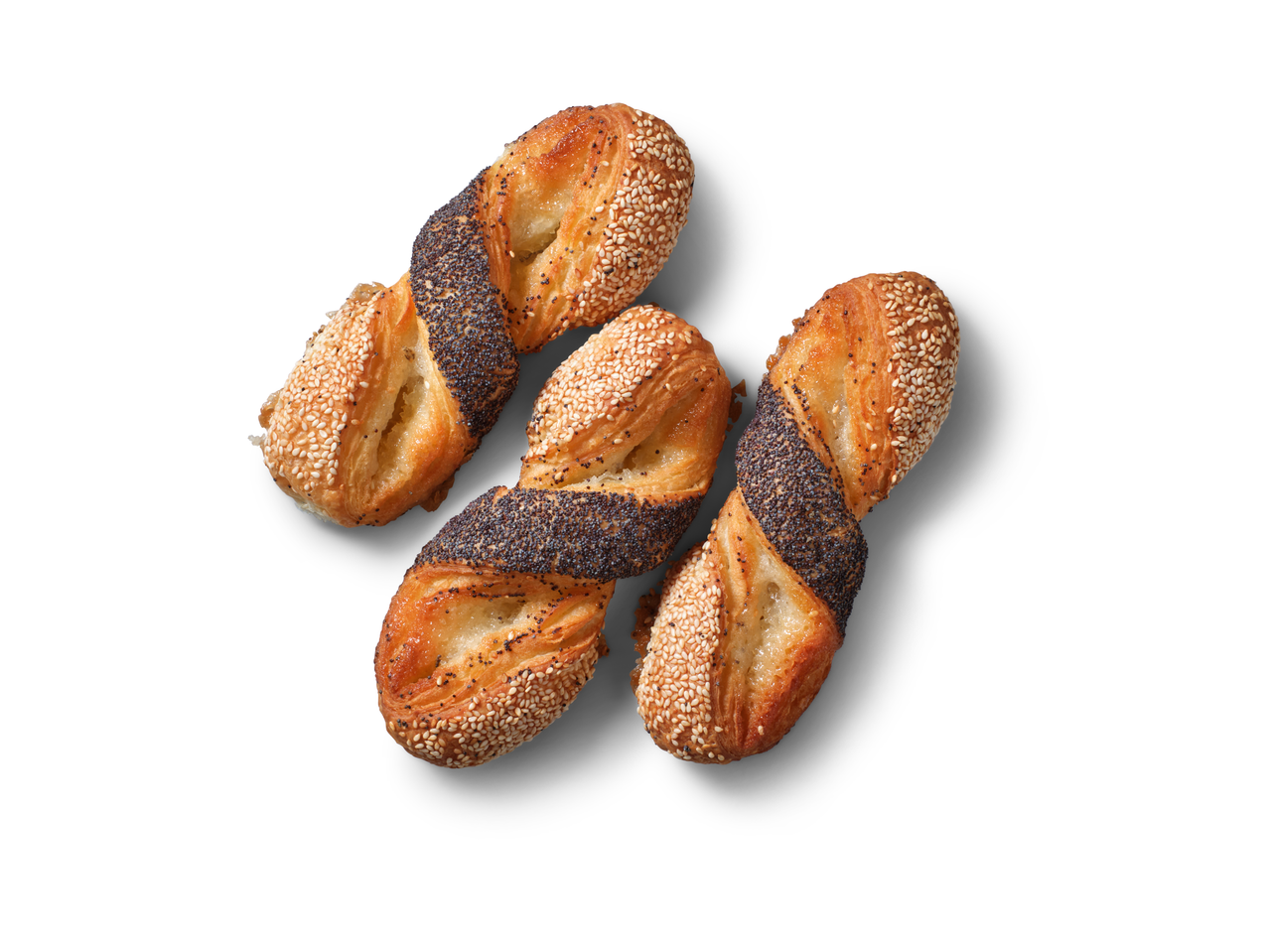 Trīs marcipāna rullīši ar magoņu sēklām un sezama sēklām uz balta fona