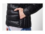 A person wearing a black puffer jacket with their hand in the pocket.