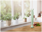Mixeur plongeant vert menthe sur une table en bois avec des ingrédients et un bol de soupe.