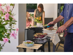 Man grilling meat and vegetables on a barbecue, using a digital thermometer.