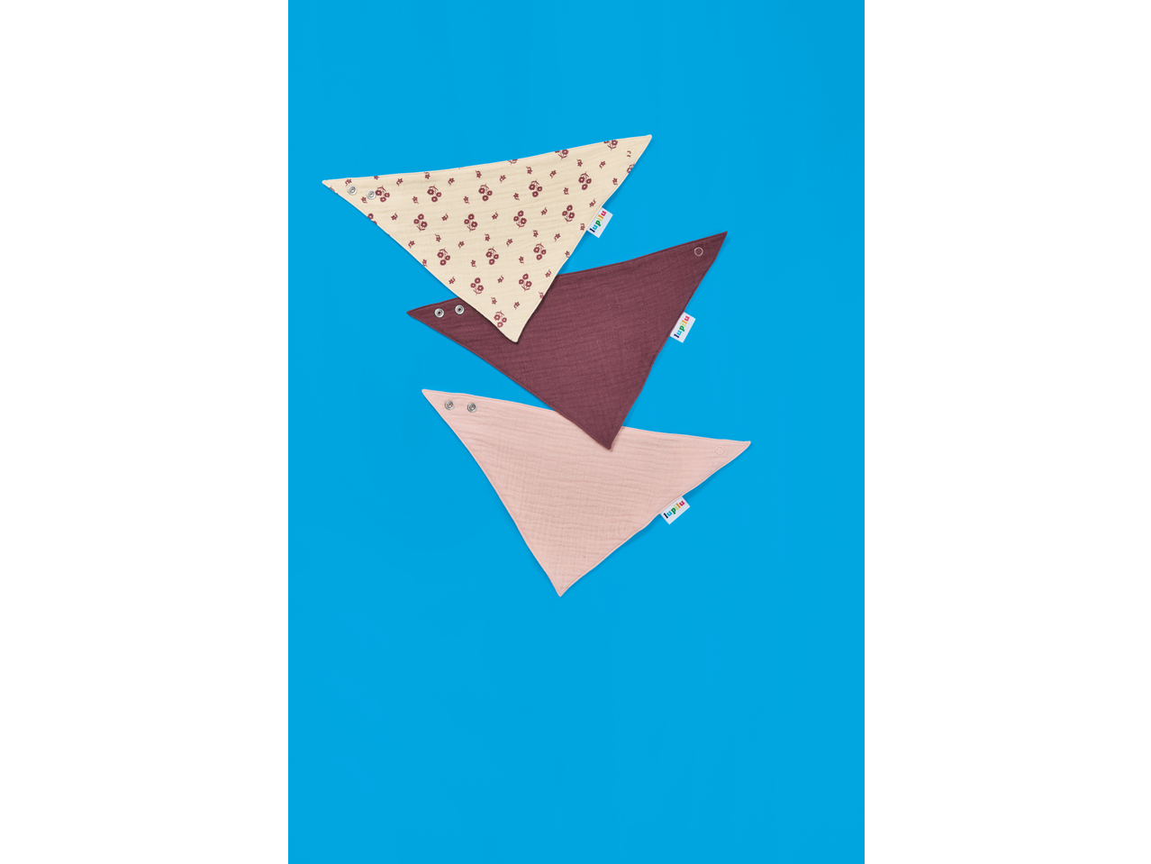 Trei bavețele din muselină Lupilu pentru bebeluși: una bej cu flori, una vișinie și una roz.