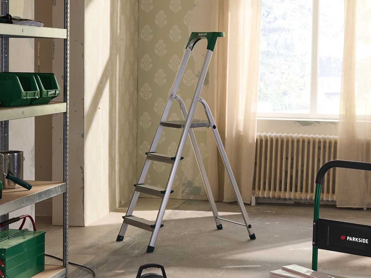 A stepladder in a room undergoing renovation, with shelving units and painting supplies.