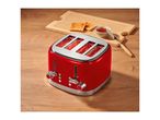 Red four-slice toaster on a wooden table next to toast and jam