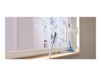 Window cleaner with telescopic handle and squeegee cleaning a window with suds.