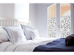 Um quarto com uma cama branca, almofadas brancas e um cobertor azul.