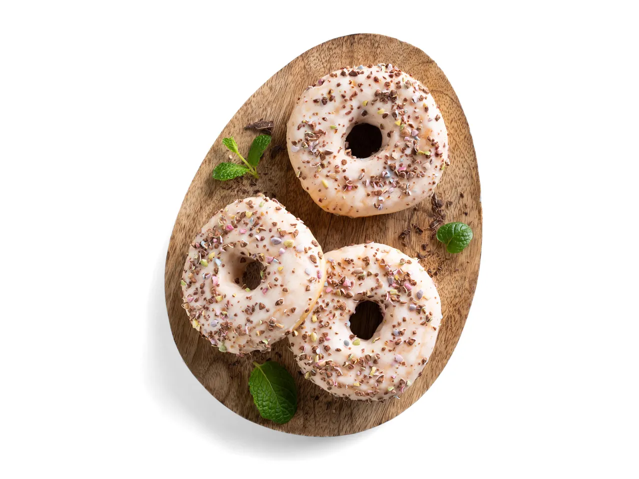 Három fánk fehér mázzal és színes szórással egy fa tálcán, menta levelekkel díszítve.