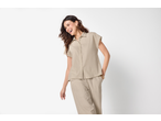 Femeie zâmbitoare purtând o cămașă și pantaloni ESMARA de culoarea nisipului.