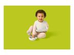 Happy baby in a bib, holding a bowl and spoon, ready to eat.