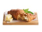 Croissant med smør på et bambusbræt.