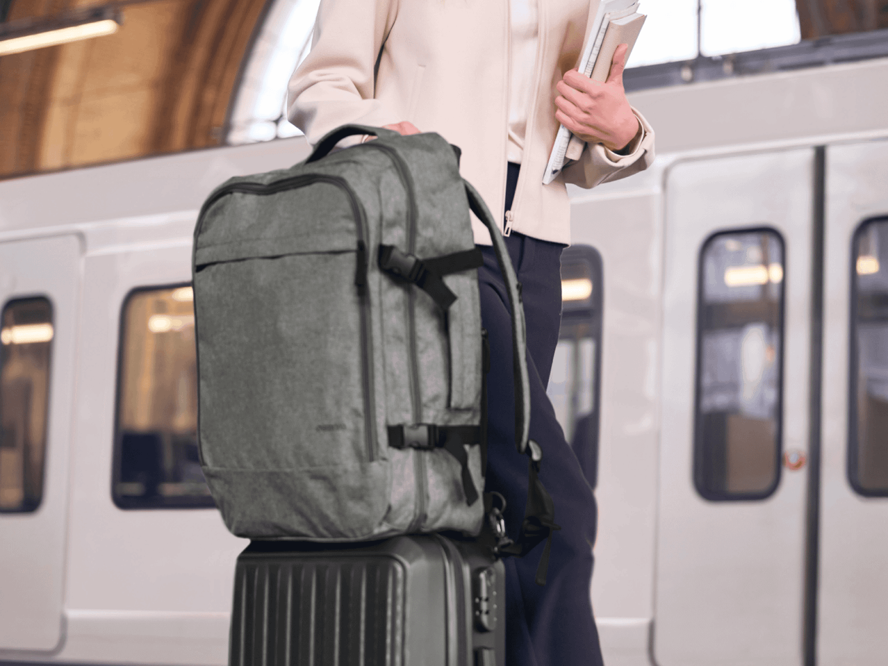 Frau mit Rucksack und Rollkoffer am Bahnsteig, bereit für die Reise.