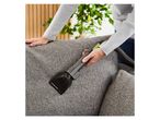 A person cleaning a gray sofa with a Hurricane Cat 2 vacuum attachment.