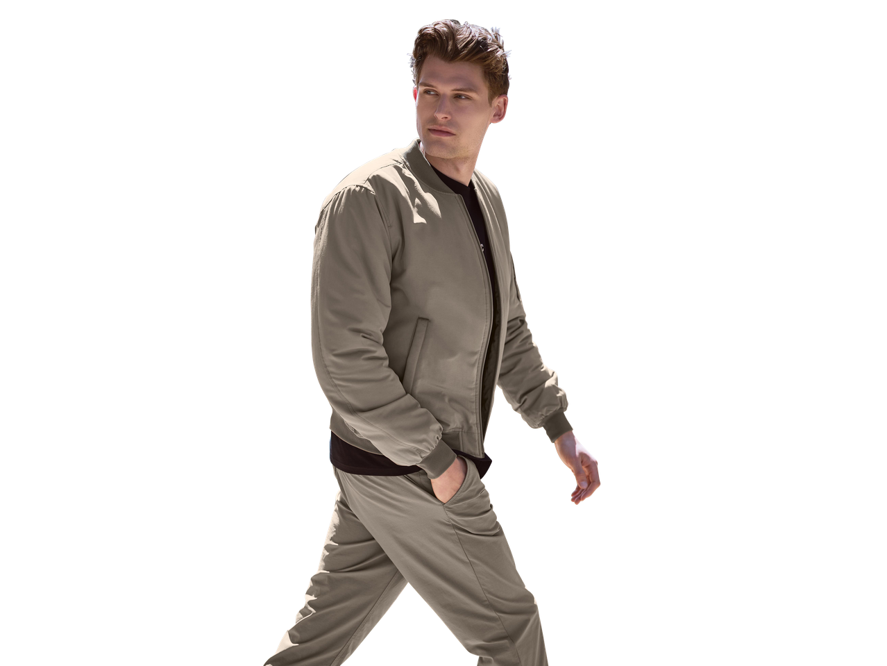 Férfi bézs bomberdzseki és nadrág, fekete pólóval, oldalra nézve.