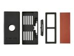 A black sharpening stone holder with a round hole, a slotted insert, a small sharpener, a frame, and a red sharpening stone.