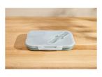 Light green lunch box with a transparent lid and built-in cutlery on a wooden table.