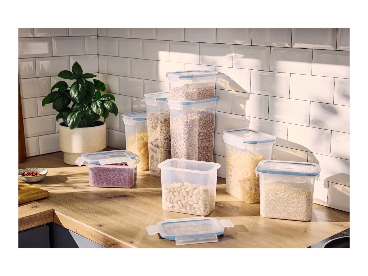 A selection of airtight plastic food storage containers filled with dry goods on a kitchen counter.