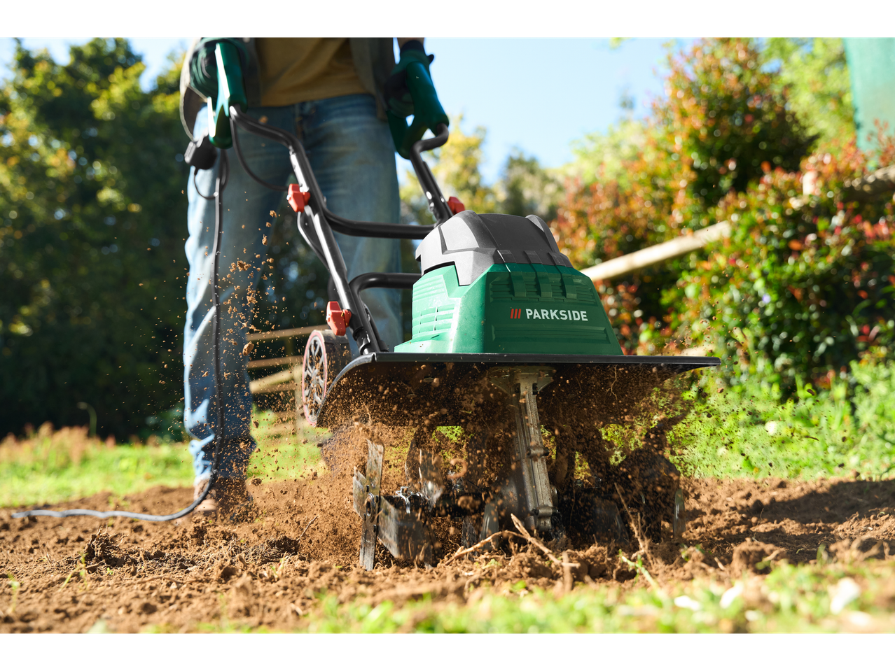 Градински култиватор Parkside® в действие, обработва почвата в градина.
