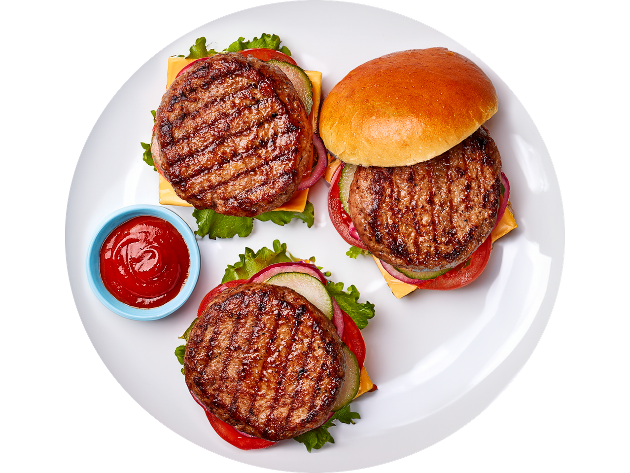 Three grilled beef burgers with cheese, lettuce, tomatoes, and pickles on a plate with ketchup.