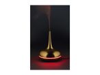 Gold-colored essential oil diffuser with red LED light emitting mist against a dark background