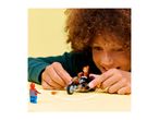 A child playing with a toy motorcycle and a superhero figurine on a yellow surface.