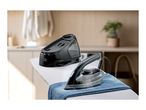 A black steam generator iron on an ironing board with a blue cloth.