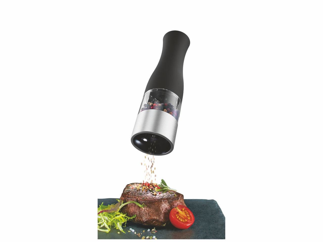 Moulin à poivre électrique noir en action, assaisonnant un steak.