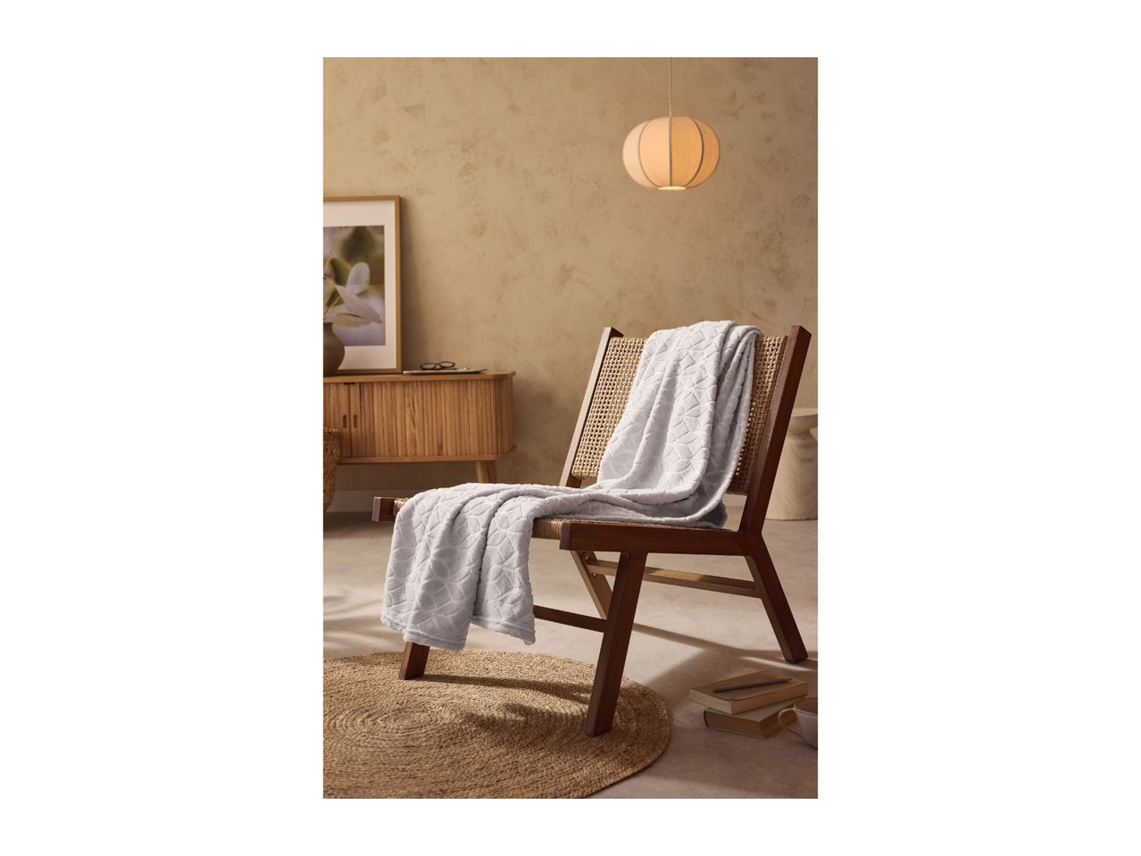 A light gray blanket draped over a wooden and wicker chair in a cozy room.