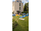 Kids playing with a Lupilu water slide, paddling pool, and sprinkler in a garden.