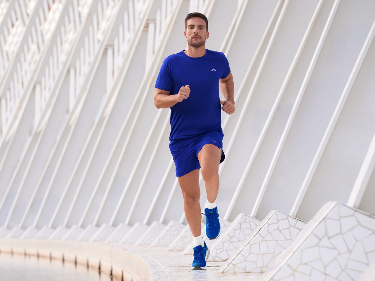 Man in blue running shirt and shorts jogging outdoors.