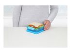 A person holding a sandwich in a blue lunchbox on a white table.