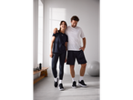 Zwei Personen in Under Armour Funktionsshirts und Sportkleidung im Fitnessstudio.