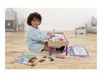 Child playing with a magnetic drawing board, puzzle, and coloring pages on a wooden floor.