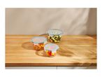 Three glass food storage containers with blue lids on a wooden countertop.