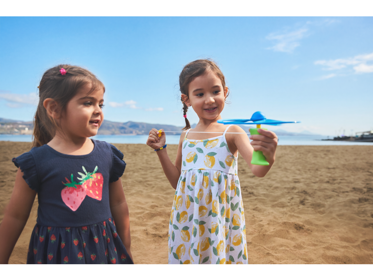 Two girls playing with Lupilu Outdoor Toy Sets on a sandy beach.