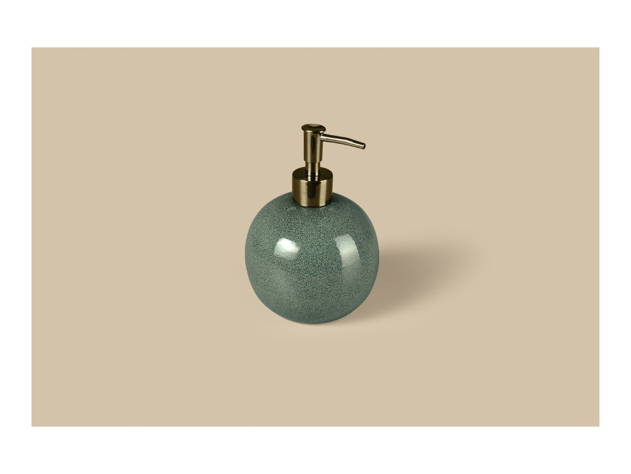 Round green soap dispenser with a gold pump on a beige background