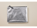 Uma necessaire prateada com zíper sobre um fundo bege.