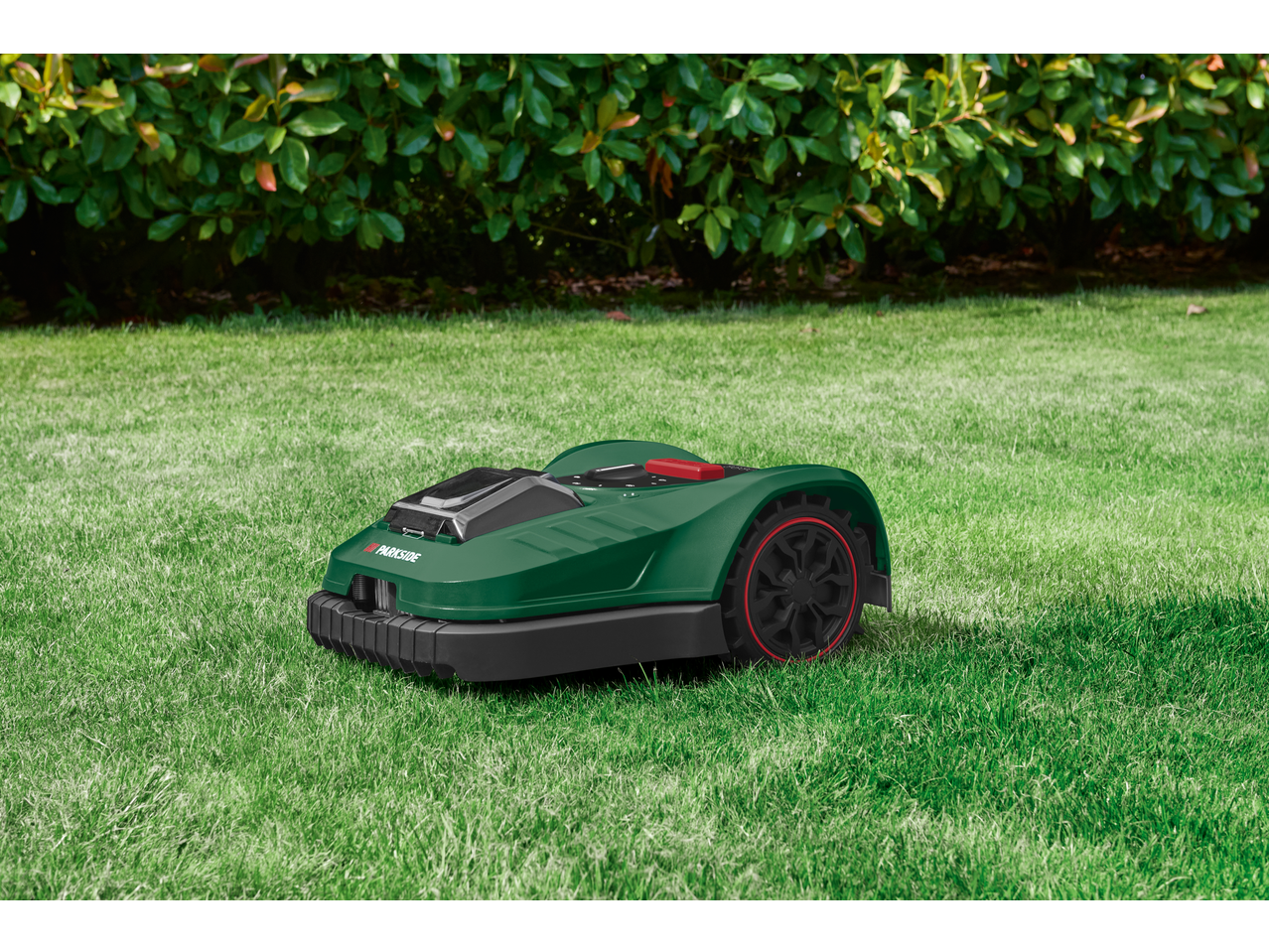 PARKSIDE® 20V Robot Lawn Mower on green grass with a hedge in the background.