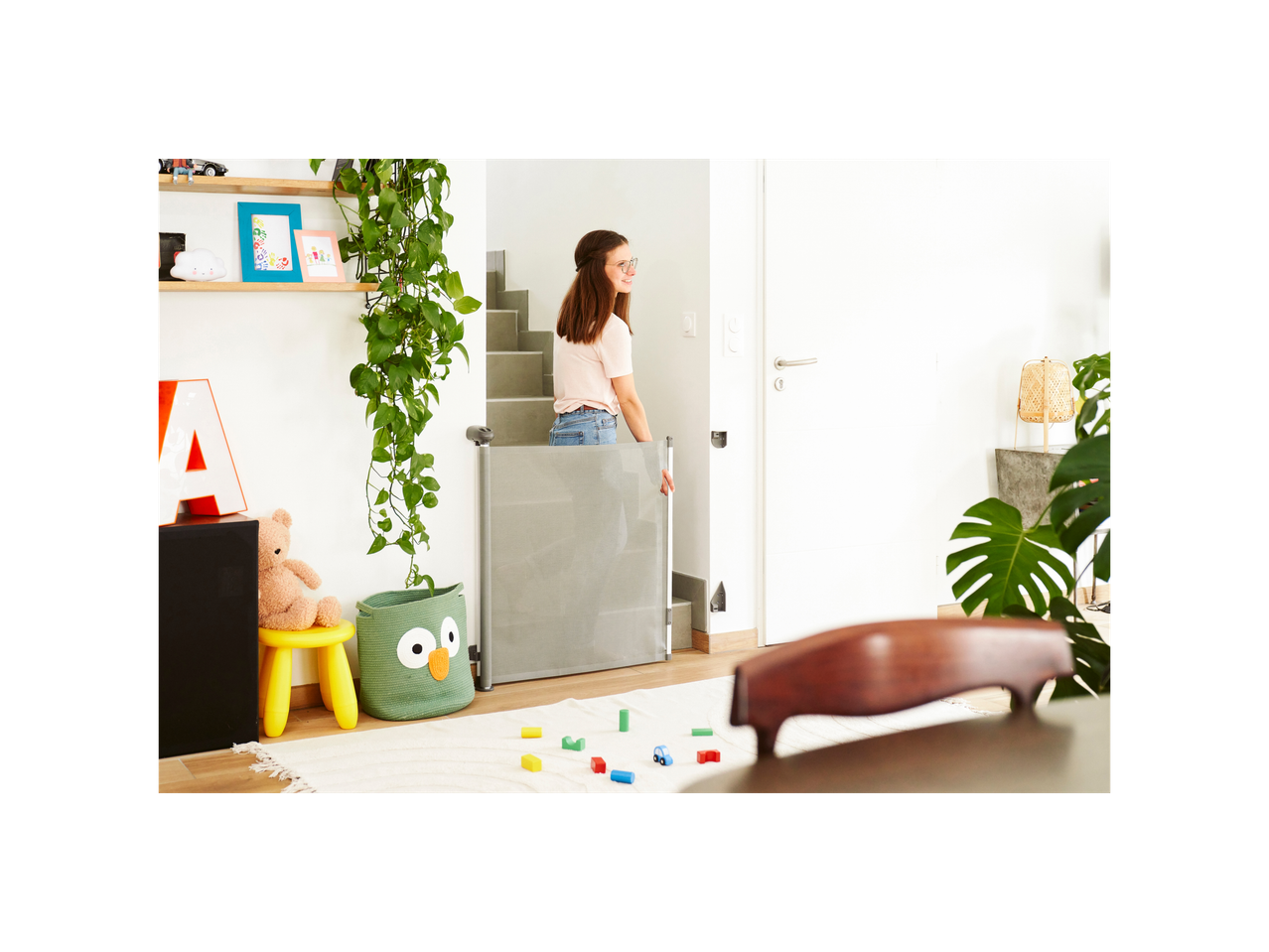 Gray Badabulle Safe baby gate separating a living room from a staircase.