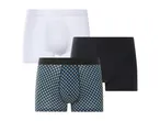 Un set di tre boxer da uomo: uno bianco, uno nero e uno con motivo geometrico blu e nero.