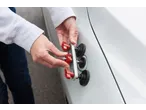 Hands using a Parkside® Dent Repair Kit on a white car.