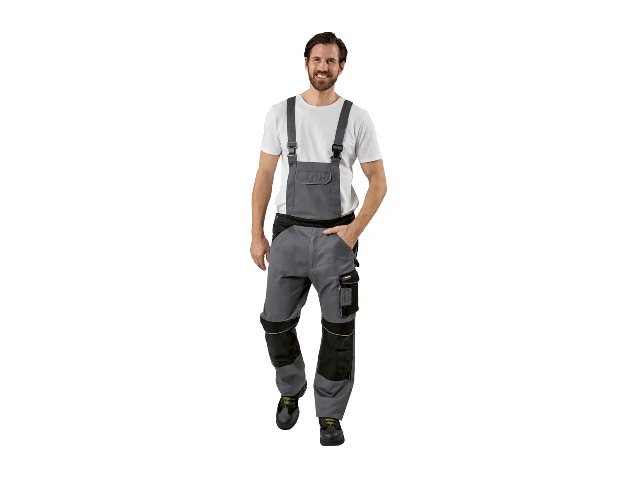 Man in gray work overalls and a white t-shirt, smiling at the camera.