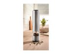 Stainless steel electric pepper mill with peppercorns on a wooden kitchen counter.